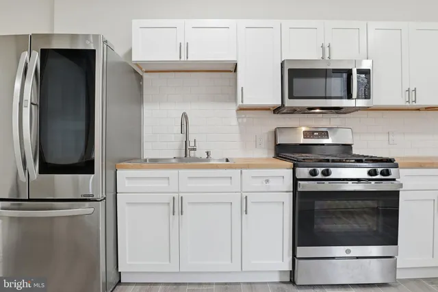 a kitchen with stainless steel appliances a stove microwave and sink