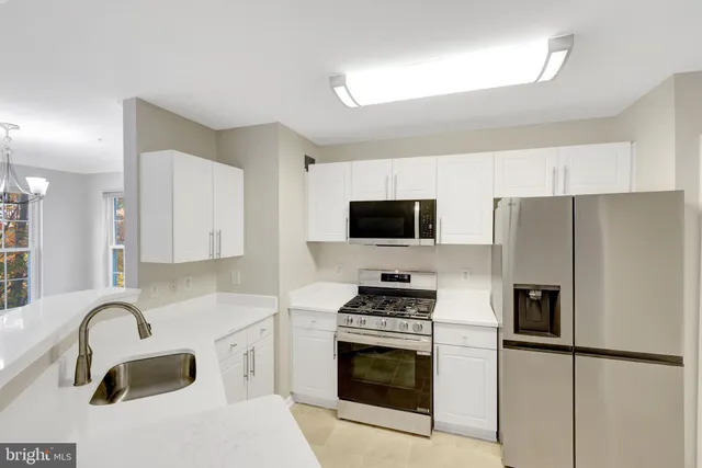 a kitchen with stainless steel appliances a refrigerator sink and white cabinets