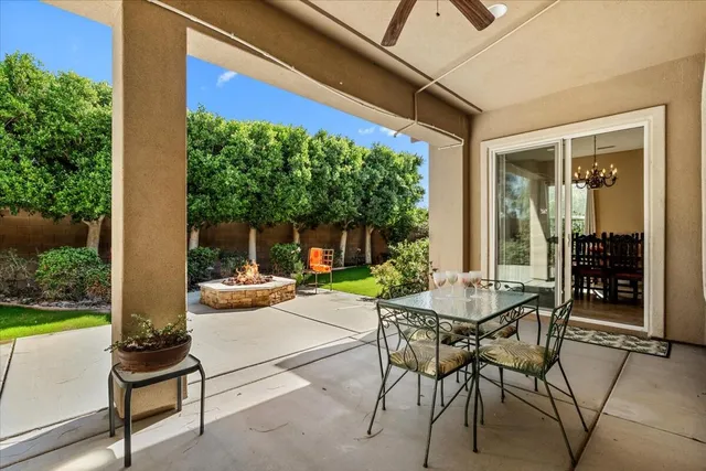 a view of a patio with table and chairs potted plants and floor to ceiling window