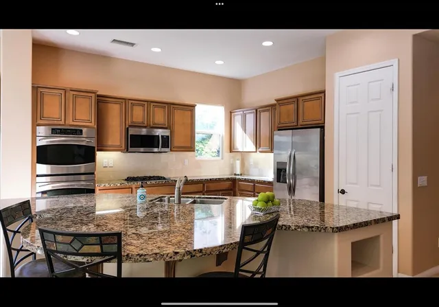 a kitchen with kitchen island granite countertop a stove a sink a microwave and a refrigerator