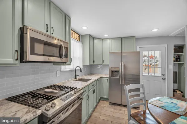 a kitchen with stainless steel appliances granite countertop a stove a sink dishwasher a refrigerator and a microwave