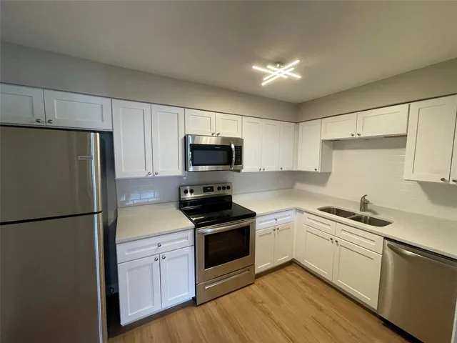 a kitchen with white cabinets sink and stainless steel appliances