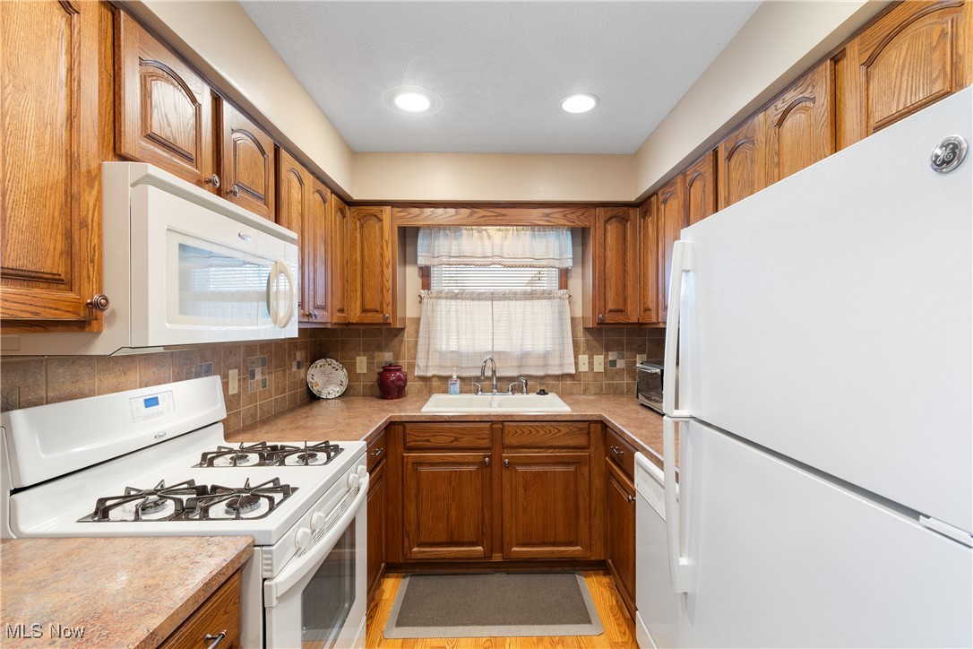 447 Center Road Bedford, OH 44146 - Photo 9 of 33 Kitchen featuring brown cabinetry, white appliances, light countertops, and a sink