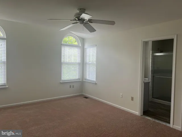 an empty room with windows and chandelier fan