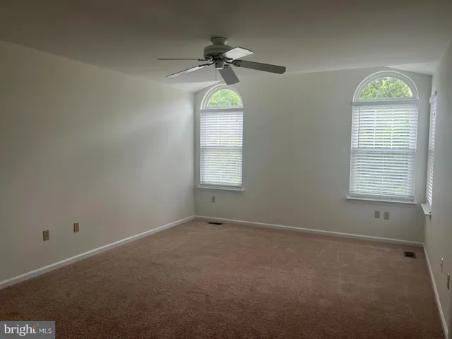 an empty room with a window and a chandelier fan