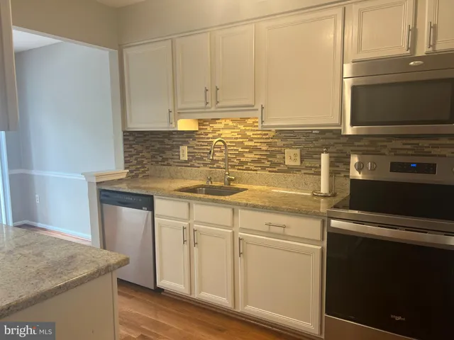 a kitchen with granite countertop white cabinets and white appliances