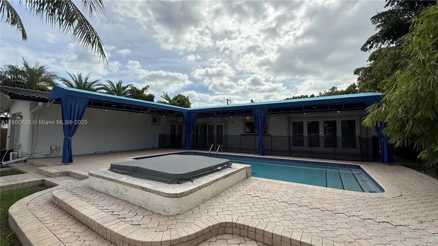 a backyard of a house with table and chairs and potted plants