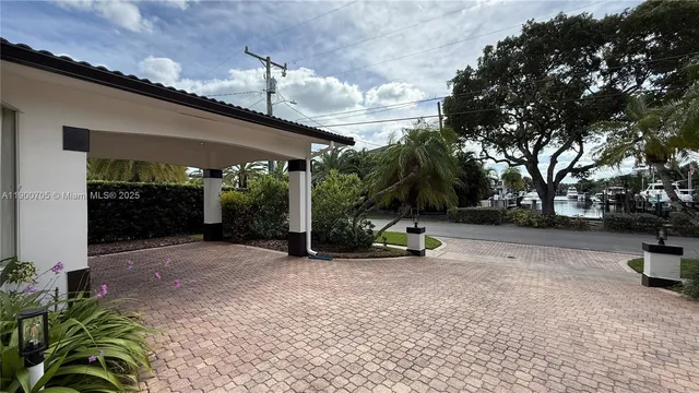 a view of a white house with a bench and potted plants
