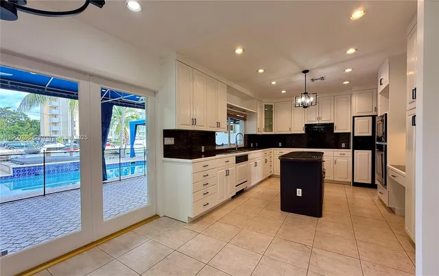 a large kitchen with stainless steel appliances kitchen island granite countertop a refrigerator oven a stove top oven and a sink with granite countertops