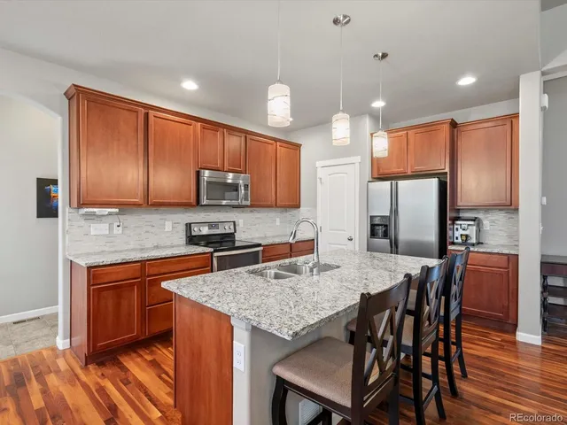 a kitchen with stainless steel appliances granite countertop table chairs refrigerator and microwave