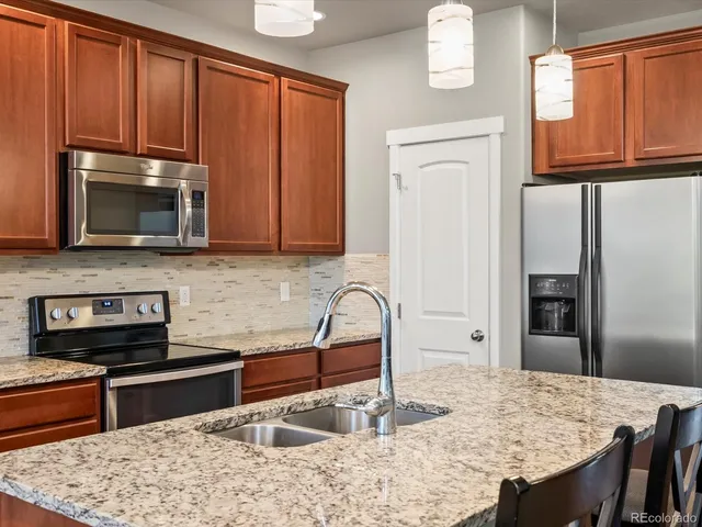 a kitchen with stainless steel appliances granite countertop a stove refrigerator sink and microwave