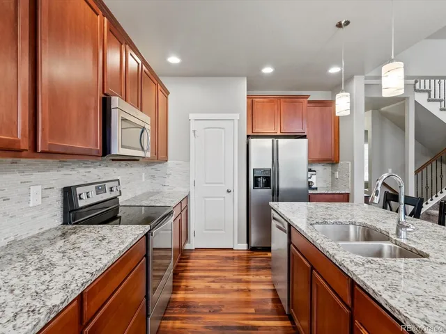 a kitchen with stainless steel appliances granite countertop a sink a stove and a refrigerator