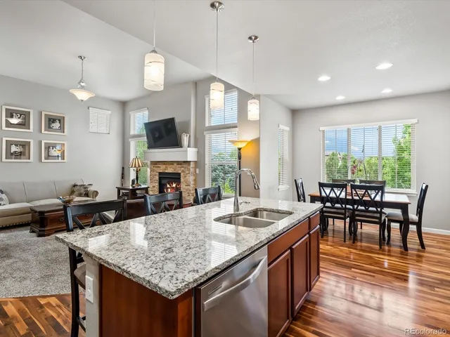 a kitchen with granite countertop a stove a sink a dining table and chairs