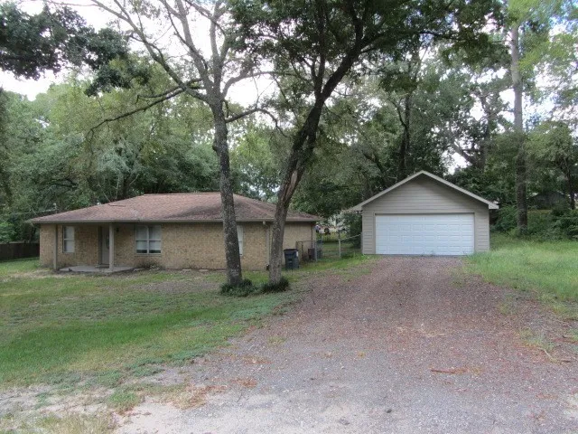 a view of a house with a yard and large trees