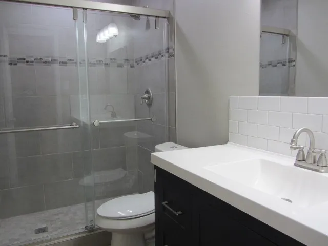 a bathroom with a sink a toilet and shower