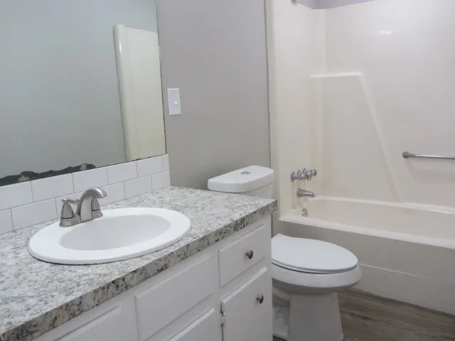 a bathroom with a granite countertop sink a toilet and bathtub