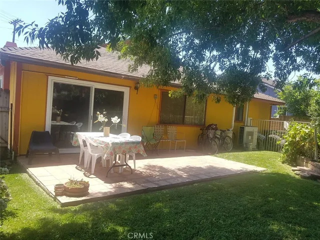 a view of a backyard with table and chairs potted plants and a large tree