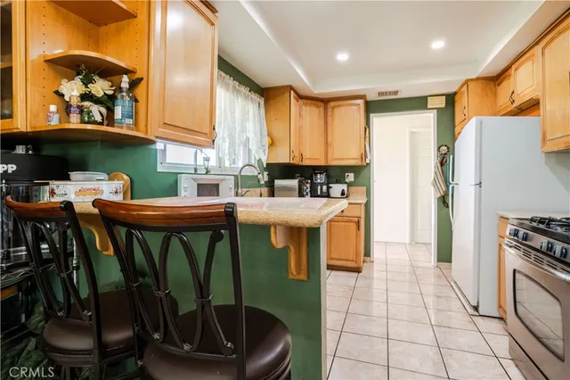 a kitchen with stainless steel appliances granite countertop a refrigerator a sink a stove and a dining table with wooden floor