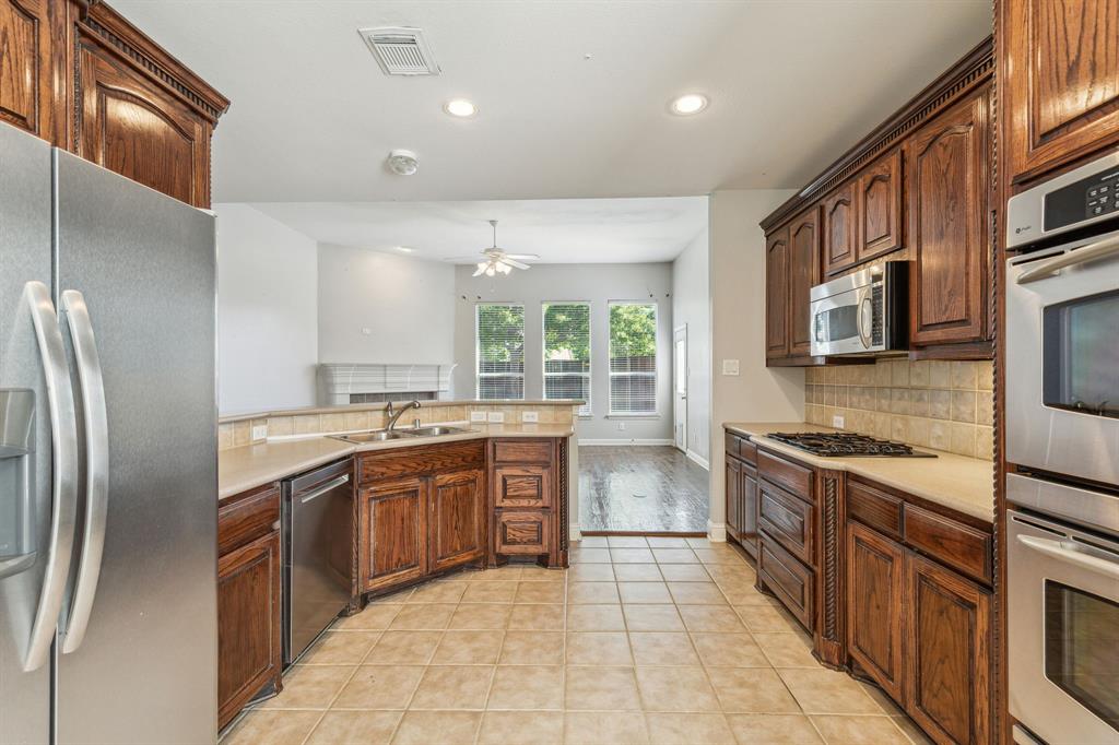 3370 Nation Drive Frisco, TX 75034 - Photo 12 of 37 a large kitchen with stainless steel appliances granite countertop a stove top oven a sink dishwasher a refrigerator and cabinets