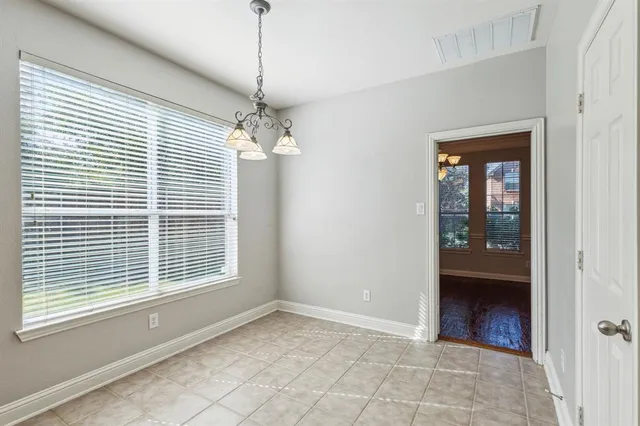 a view of an empty room with a window and a chandelier