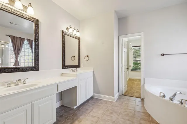 a bathroom with a tub a sink and mirror