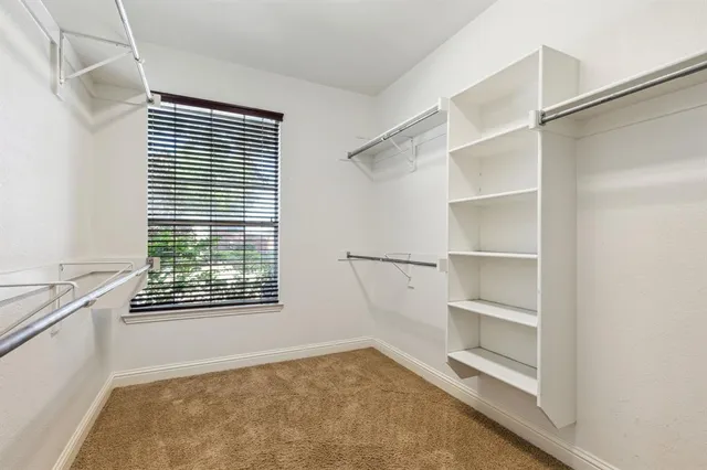 a view of an empty room with a window and cabinet