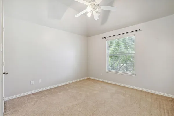 an empty room with a window and a fan