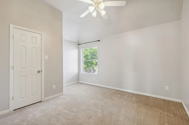 an empty room with windows and fan