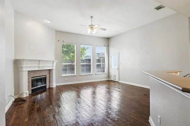 a view of an empty room with wooden floor fireplace and a window