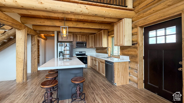 5236 North Holly Way Helper, UT 84526 - Photo 8 of 34 Kitchen featuring appliances with stainless steel finishes, log walls, dark wood-style flooring, light countertops, and wooden ceiling with exposed beams