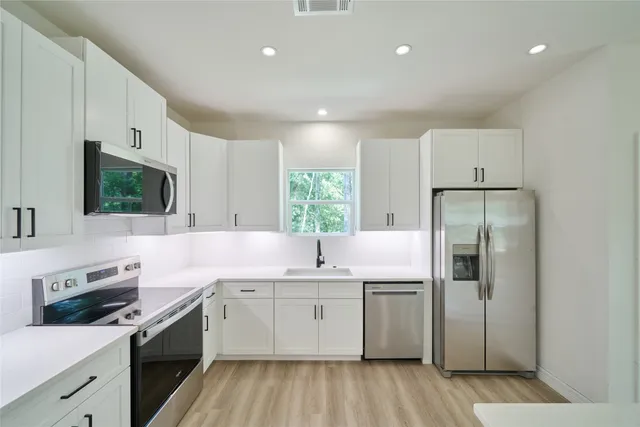 a kitchen with a sink cabinets stainless steel appliances and a window