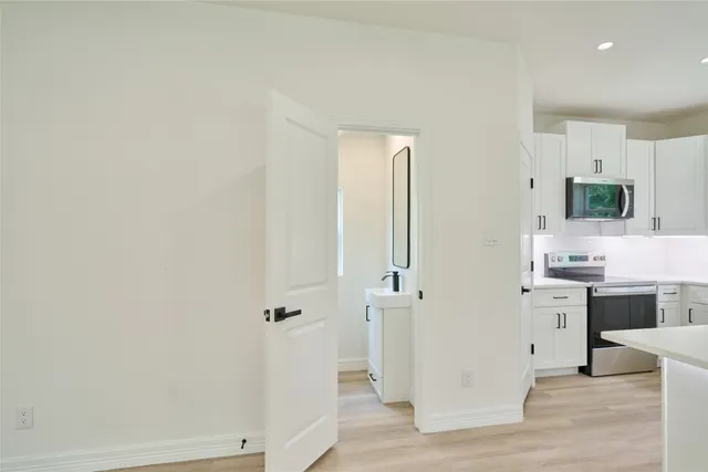 a view of a kitchen with white cabinets and wooden floor
