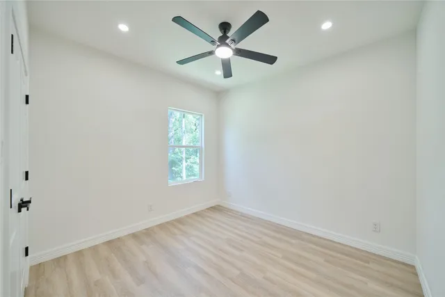 an empty room with wooden floor and ceiling fan