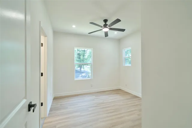 a view of an empty room with wooden floor and a window