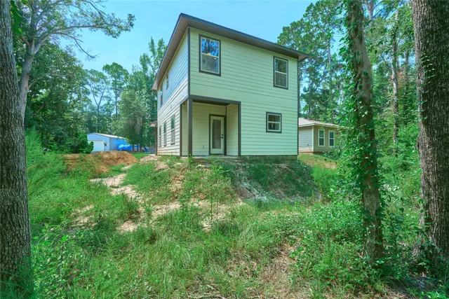 an aerial view of a house with a yard and trees all around