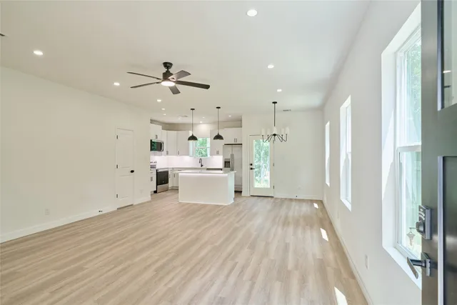 a view of a kitchen with wooden floor electronic appliances and a window