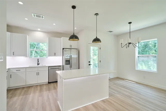 a large kitchen with kitchen island white cabinets and stainless steel appliances