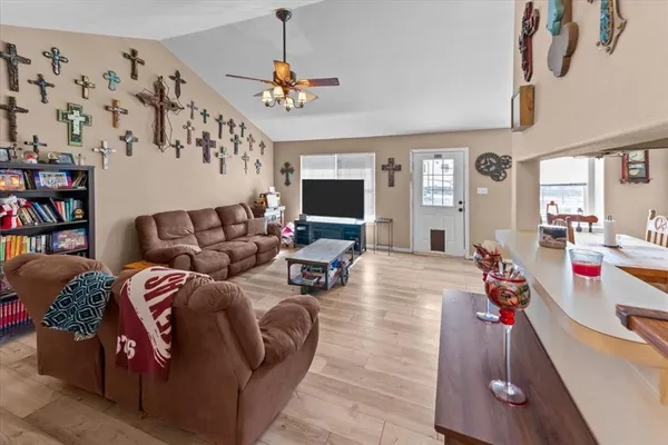 a living room with furniture kitchen view and a wooden floor