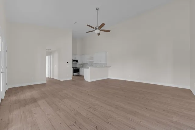 a view of empty room with wooden floor and ceiling fan