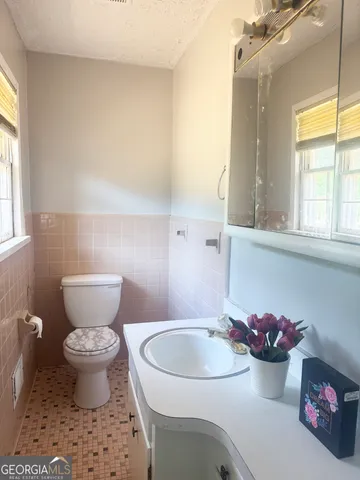 a bathroom with a sink toilet mirror and window