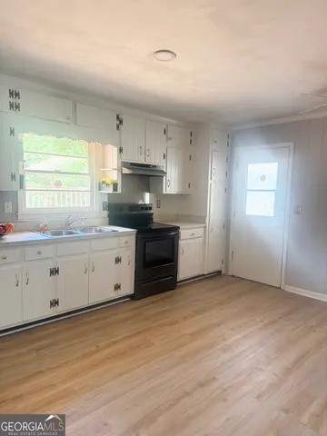 a kitchen with granite countertop a sink cabinets stainless steel appliances and a window