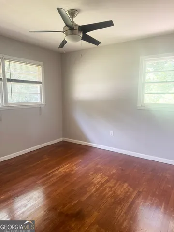 an empty room with wooden floor fan and windows