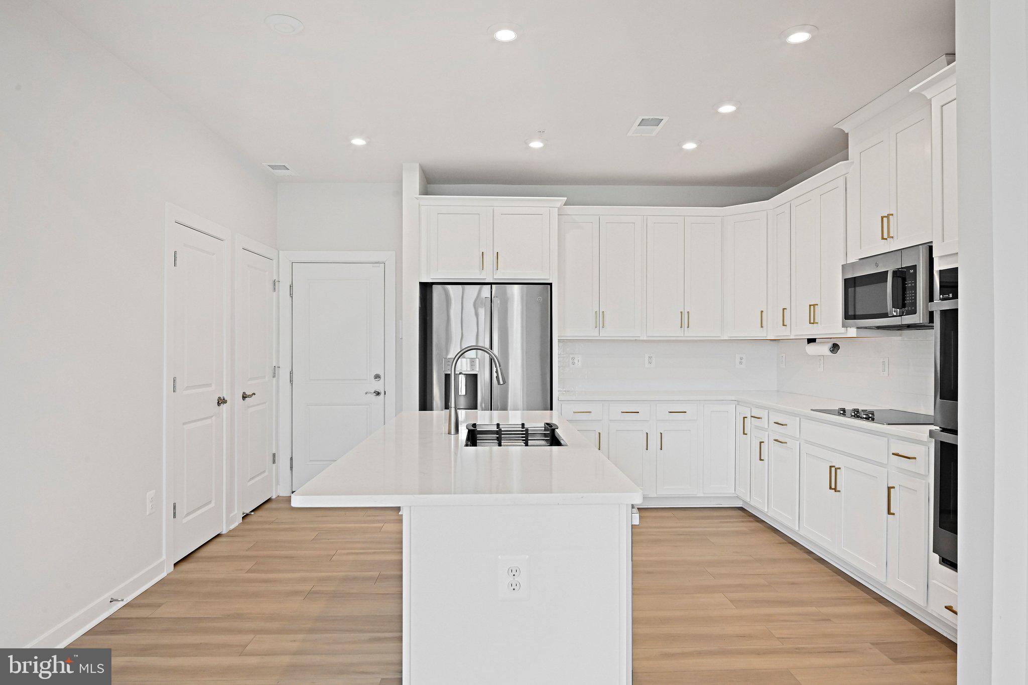 13556 Innovation Station Loop, Unit 15A Herndon, VA 20171 - Photo 5 of 28 a kitchen with stainless steel appliances granite countertop a refrigerator and a stove top oven