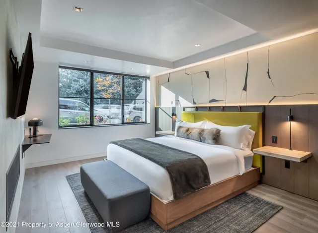 a bedroom with a bed and a flat tv screen on dresser