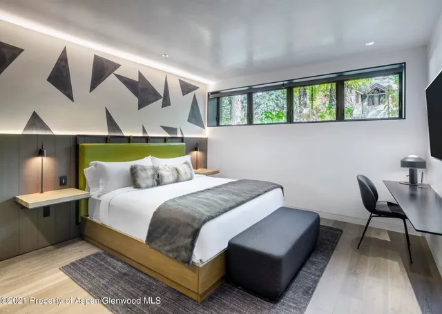 a bedroom with a bed a chandelier and a window