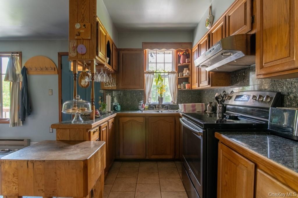 139 Haddock Road Monticello, NY 12701 - Photo 20 of 40 Kitchen with black / electric stove, under cabinet range hood, backsplash, a peninsula, and light tile patterned floors