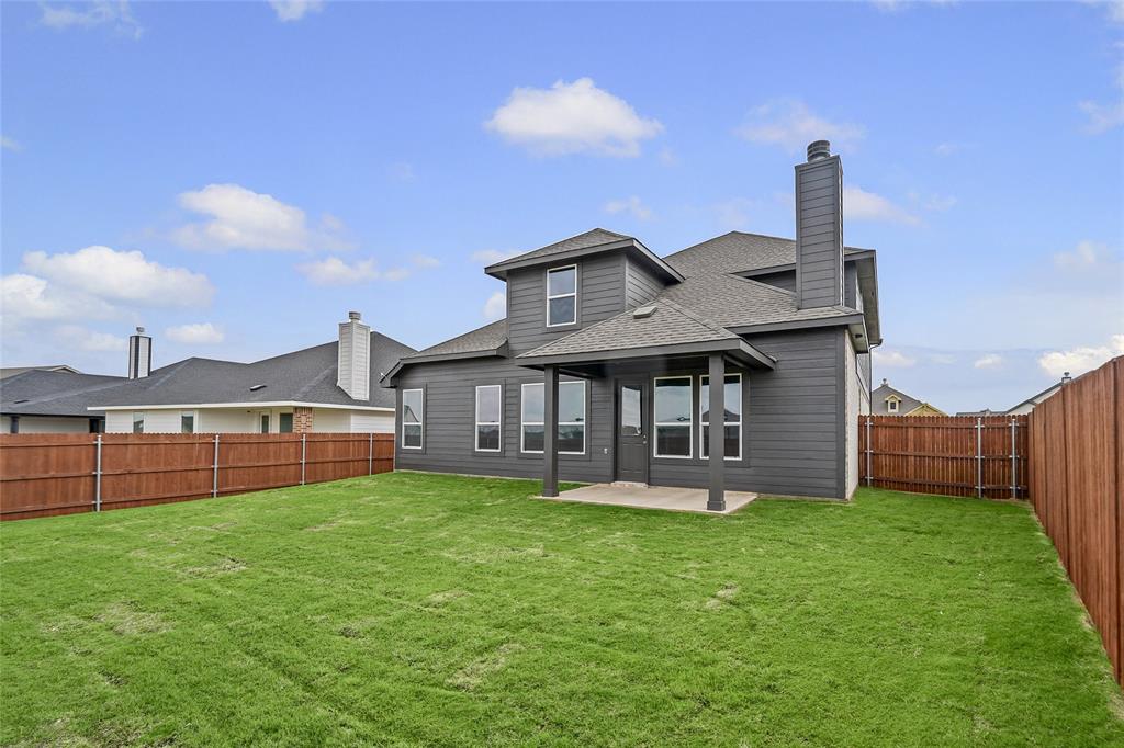 1205 Colca Drive Springtown, TX 76082 - Photo 34 of 37 Expansive backyard featuring a manicured lawn, wood privacy fencing, a covered patio, and a two-story exterior with a prominent chimney