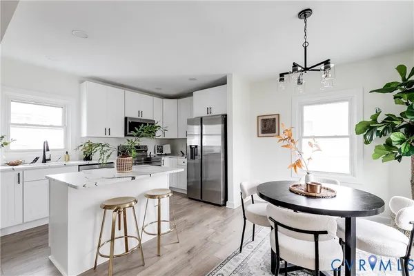 a kitchen with stainless steel appliances a dining table chairs and refrigerator