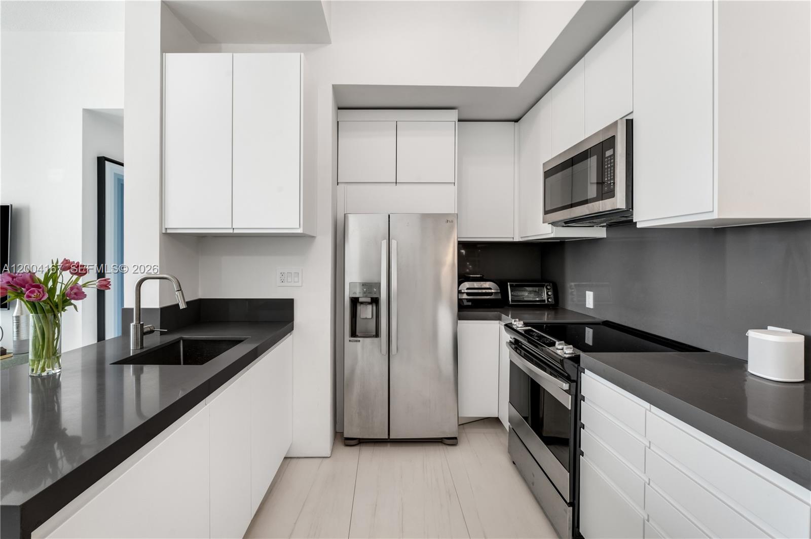 1723 Southwest 2nd Avenue, Unit PH2 Miami, FL 33129 - Photo 6 of 18 a kitchen with granite countertop a sink dishwasher stove and refrigerator with wooden floor