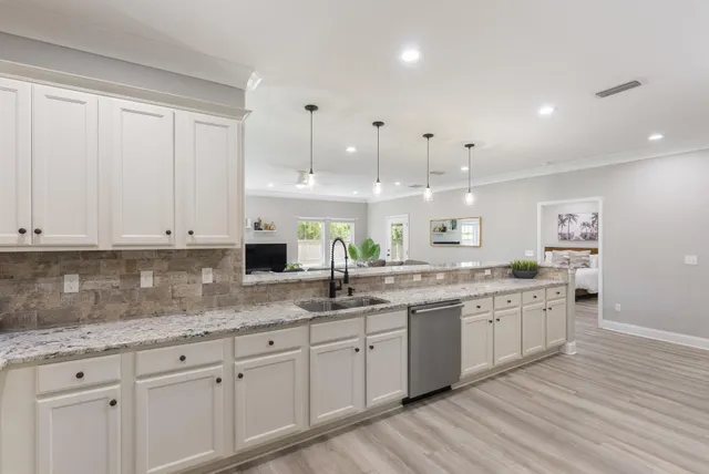 a kitchen with granite countertop white cabinets and white stainless steel appliances